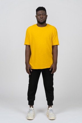 Front view of a young dark-skinned man in yellow t-shirt standing still