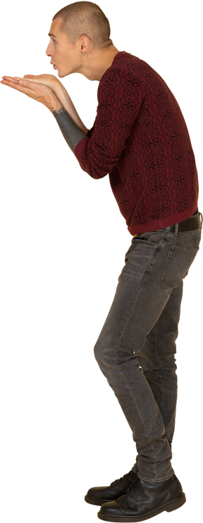 공기 키스를 보내는 빨간 스웨터에 젊은 남자의 측면보기