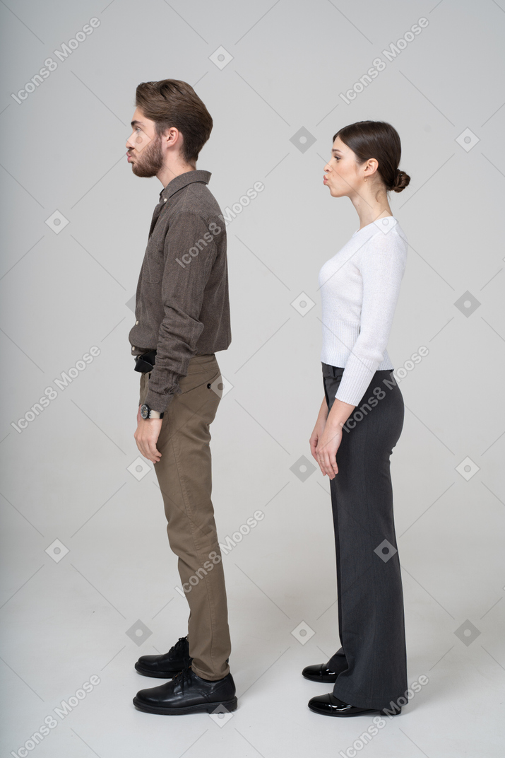 Вид сбоку молодой надутой пары в офисной одежде