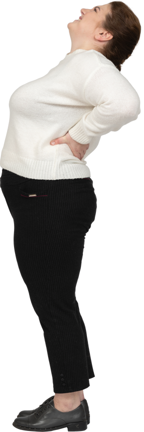 허리 통증으로 고통받는 흰색 스웨터에 통통한 여자