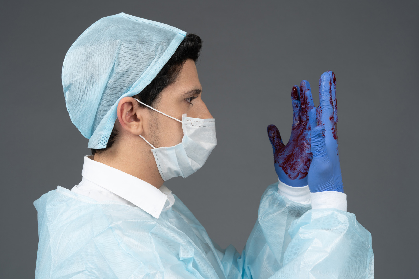 Doctor looking at his hands covered in blood in profile