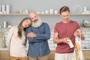 A man standing with a bag of groceries next to an older couple
