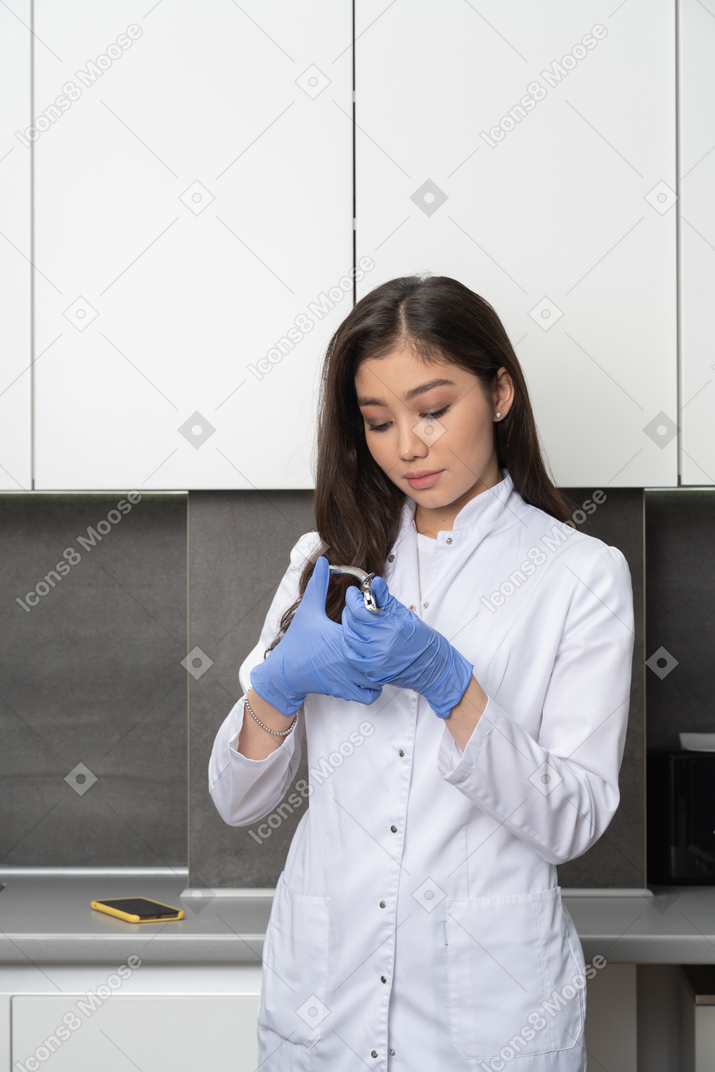 Front view of a female doctor looking attentively at her dental instrument