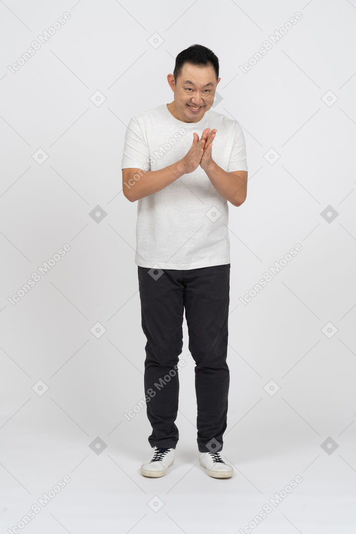 Front view of a happy man in casual clothes rubbing hands
