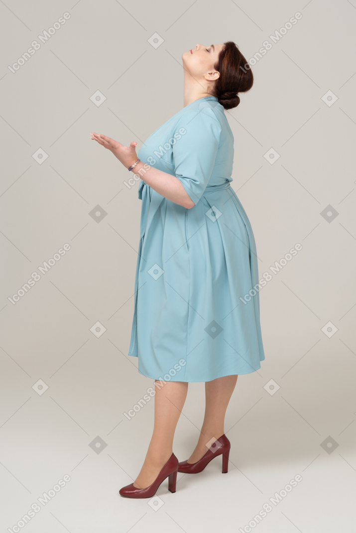 Vista laterale di una donna in abito blu che guarda in alto
