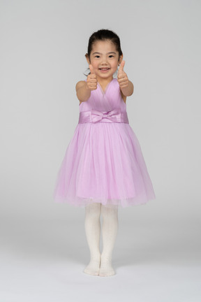 Full length photo of a little girl in a dress giving thumbs up
