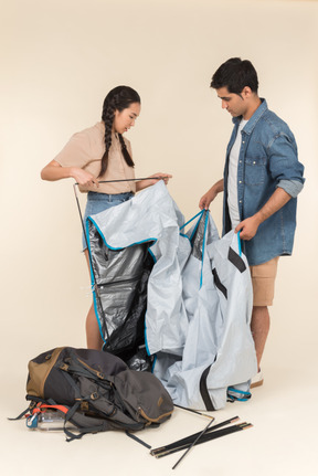 Young interracial couple setting up a tent