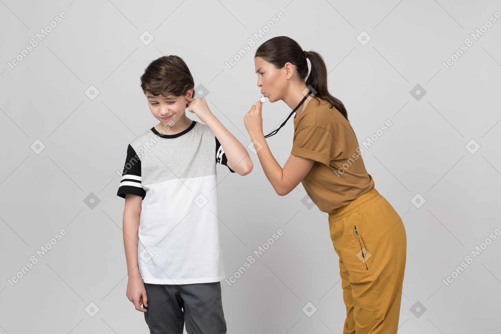 Professora de pe assobiando para seu aluno enquanto ele está fechando a orelha