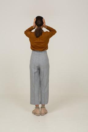 Back view of a young asian female in breeches and blouse touching head