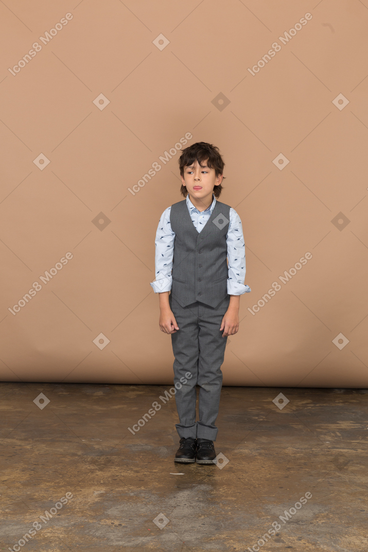 Vista frontal de um menino de terno parado