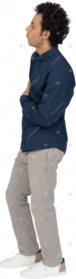 Vista laterale di un uomo in abiti casual in posa con la mano sul petto