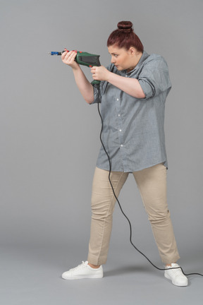 Young woman aiming with a screw driver