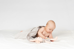 Baby in handtuch bedeckt und spielt mit spielzeug