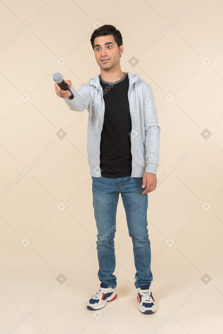 Young caucasian man holding out a microphone