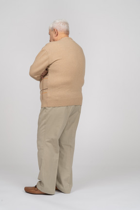 Vista laterale di un vecchio in abiti casual in piedi con le braccia incrociate