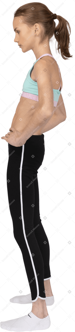 Seitenansicht eines jugendlich mädchens in der sportbekleidung, die hände auf hüften setzt