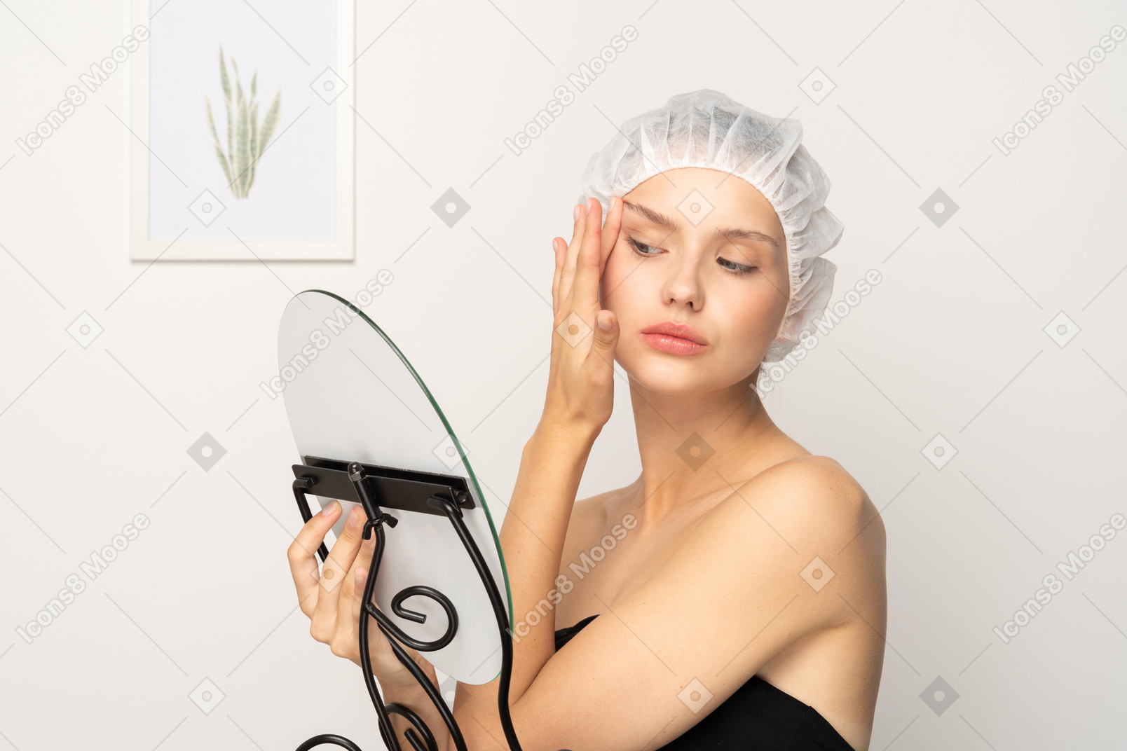 Young woman tightening her face skin while looking in the mirror