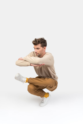 Junger mann sitzt in hip-hop-tanzposition