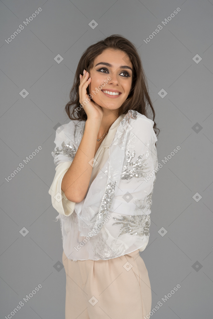 Happy young woman wrapped in white shawl daydreaming