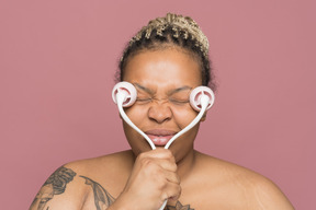 Mujer afroamericana sin camisa aplicando un rodillo de masaje facial