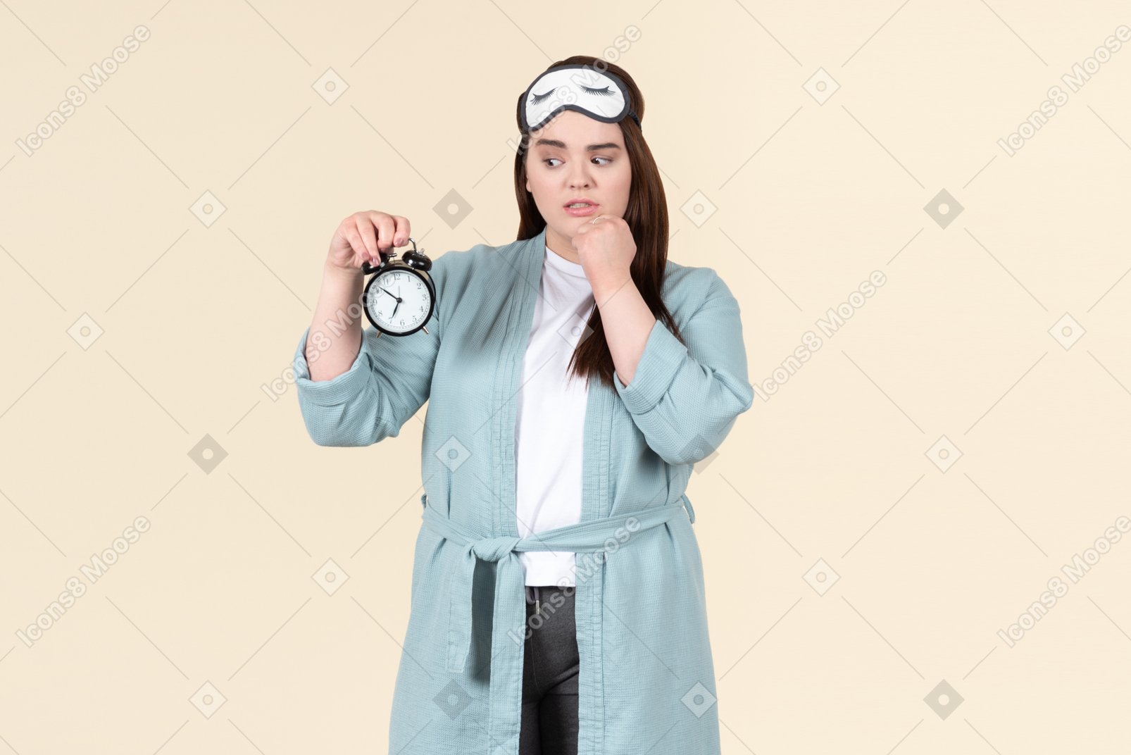 Young plus size woman in a blue bathrobe and a sleep mask on standing against a pastel yellow background, after just waking up