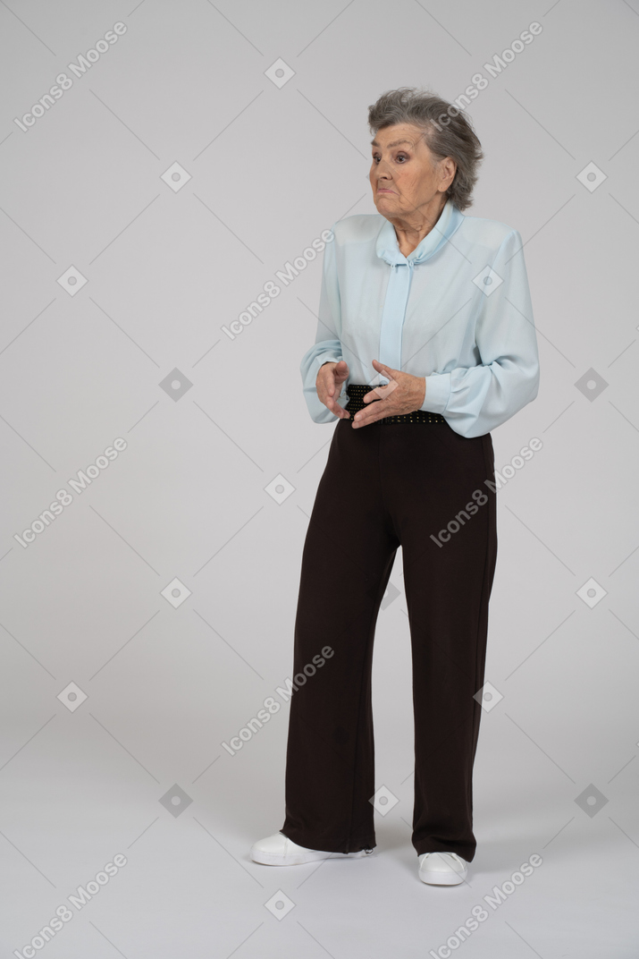 Vista frontal de una anciana encogiéndose de hombros