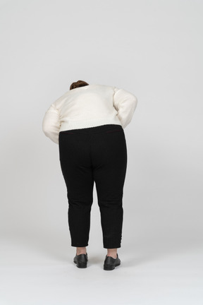 Rear view of a plump woman in white sweater bending down