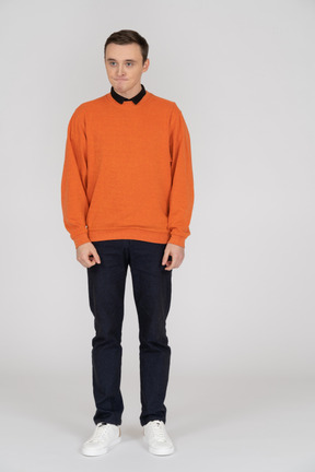 Junger mann im orangefarbenen sweatshirt stehend