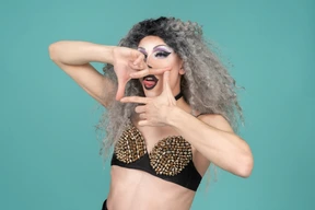 Drag queen dedo enmarcando su boca y sacando la lengua