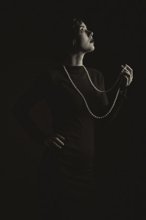 Frau mit langen perlen im dunkeln stehend