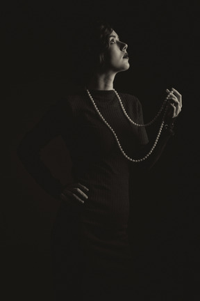 Woman with long beads standing in the dark