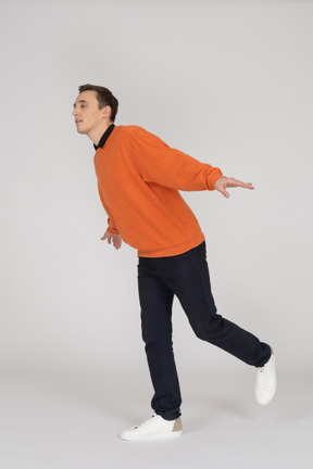Junger mann im orange sweatshirt springen
