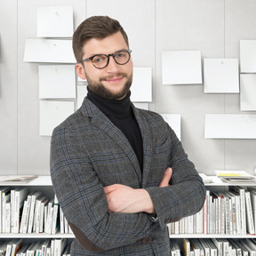 A man with glasses standing in front of a bookshelf