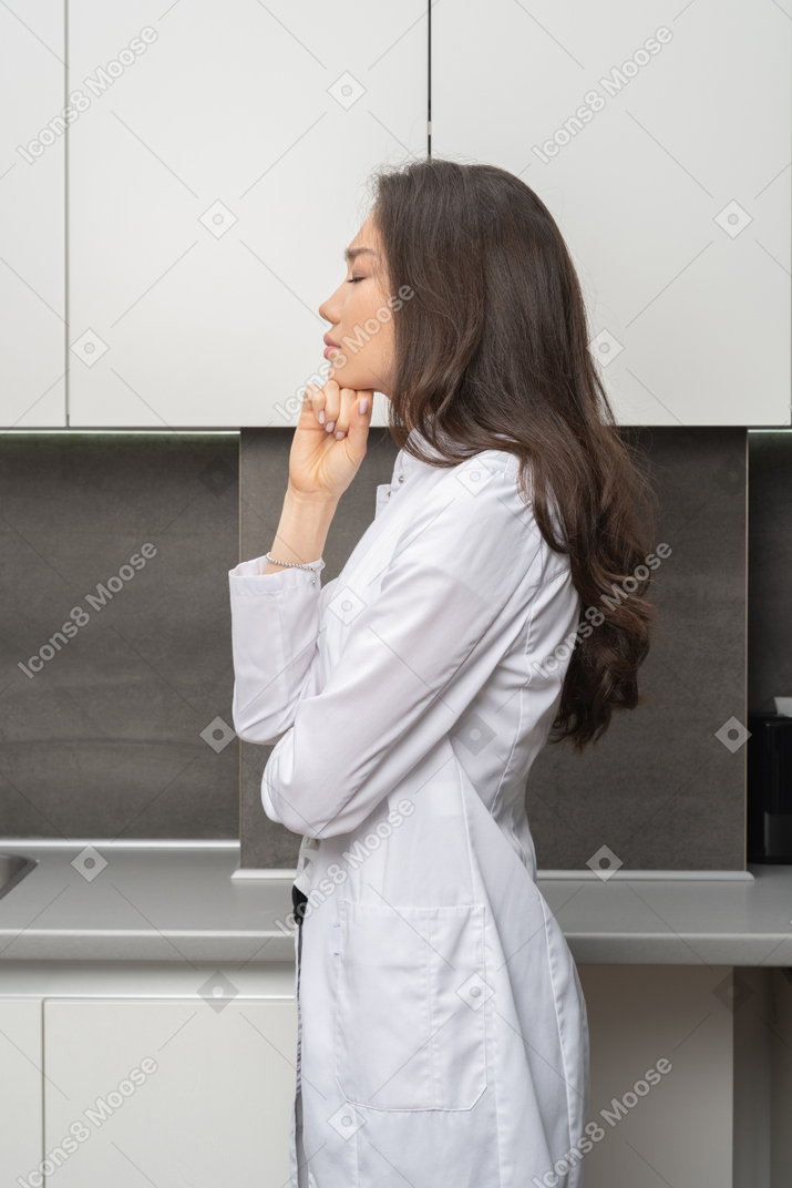 Side view of a female doctor closing hands and touching chin
