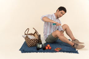 Giovane uomo caucasico seduto sulla coperta e spruzzare uno spray sulla sua gamba