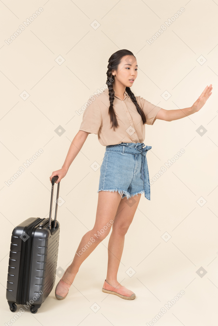 Donna con un bagaglio che chiama un taxi