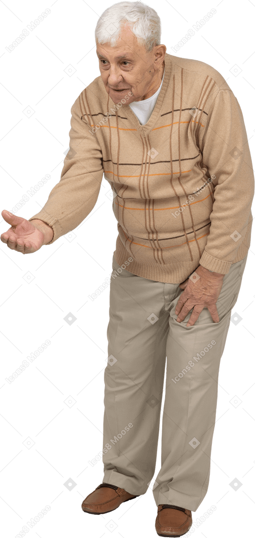 Front view of an old man in casual clothes standing with outstretched arm and explaining something