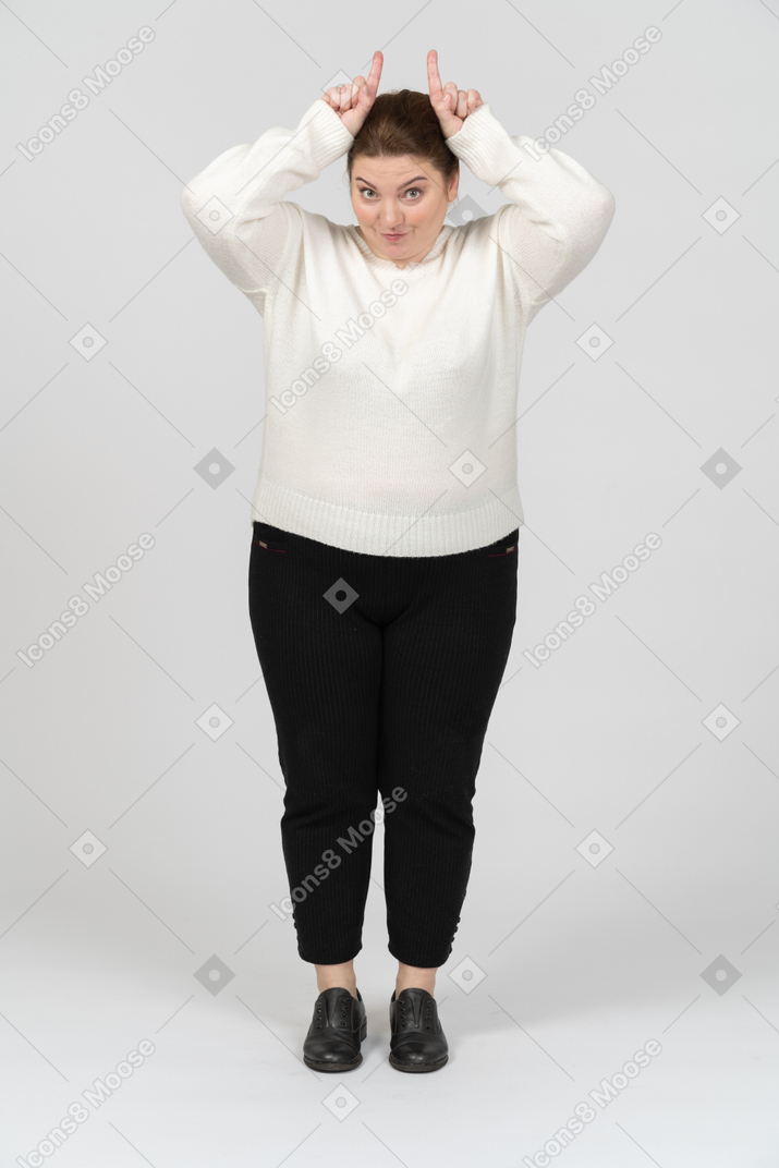 Vista frontal de uma mulher rechonchuda em roupas casuais fazendo chifres