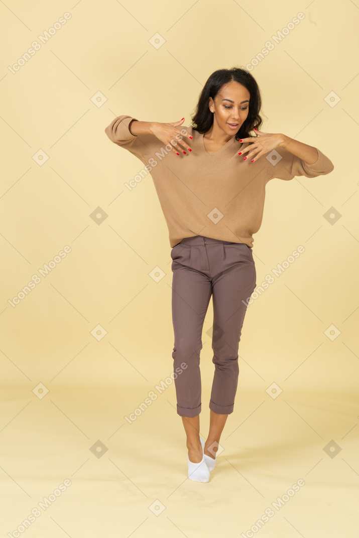 Vista frontal de una mujer joven de piel oscura levantando las manos