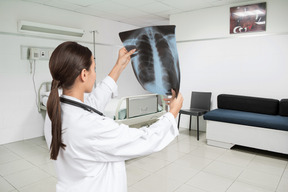 A woman in white lab coat holding up a x - ray