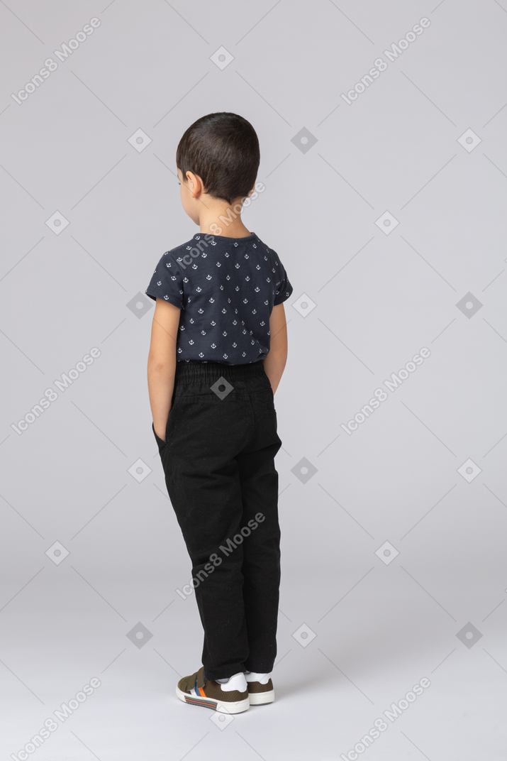 Vista trasera, de, un, niño, en, ropa informal, posición, con, manos en bolsillos