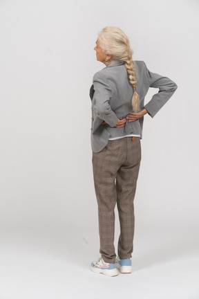 Vista trasera de una anciana en traje que sufre de dolor en la espalda