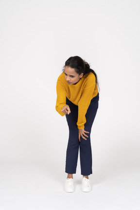 Front view of a girl in casual clothes bending down and making warning sign