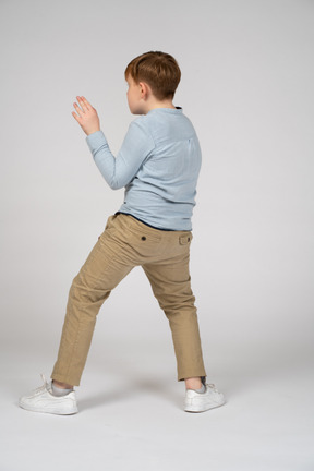 Back view of a boy standing with feet wide apart