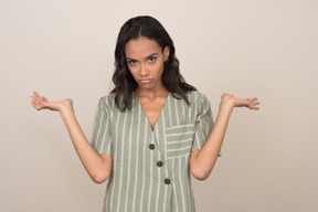 Pretty young girl with unpleased face holding hands up open aside