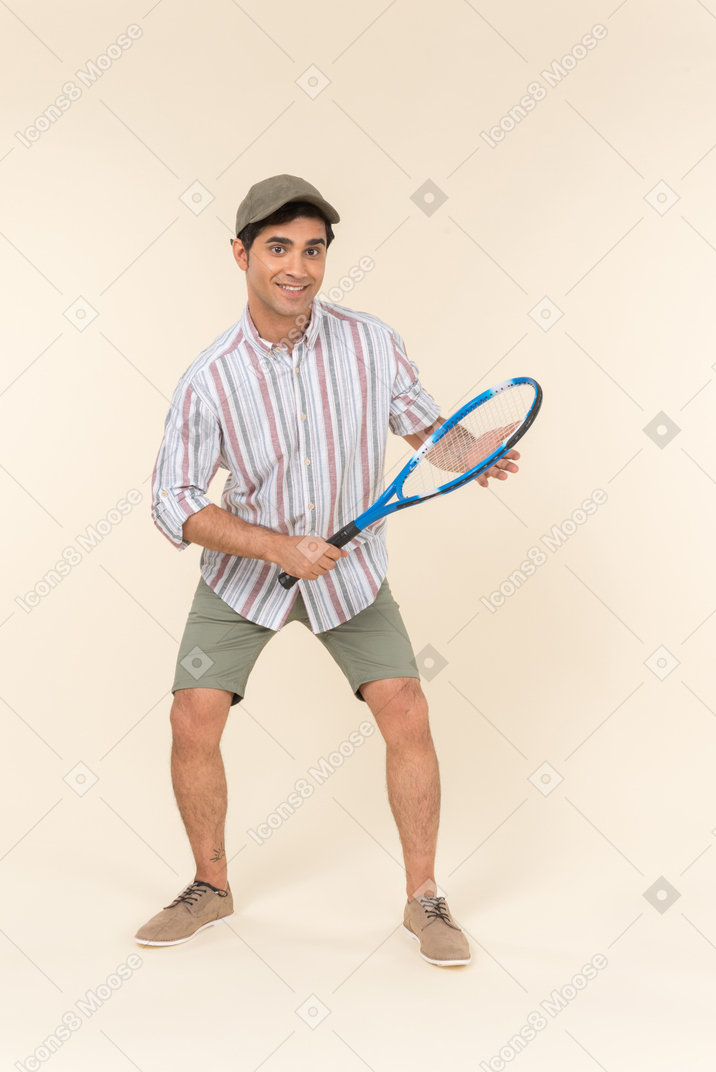 Молодой кавказский мужчина держит теннисную ракетку