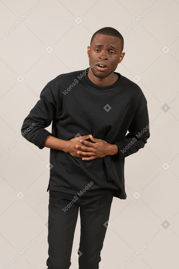 Front view of young man pretending to get shot in belly