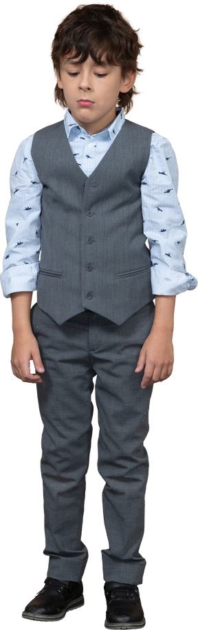 Vista frontal de un niño en traje gris parado