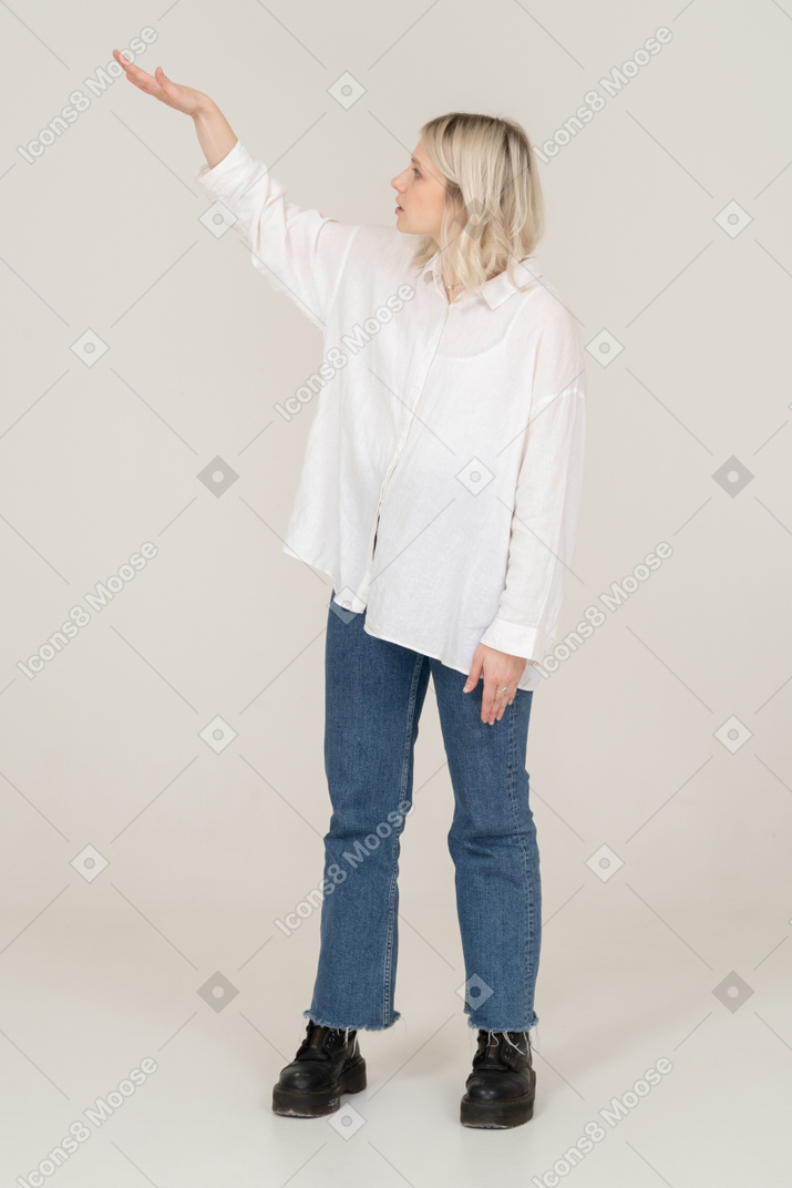 Vista frontal de una mujer rubia levantando la mano y mostrando el tamaño de algo