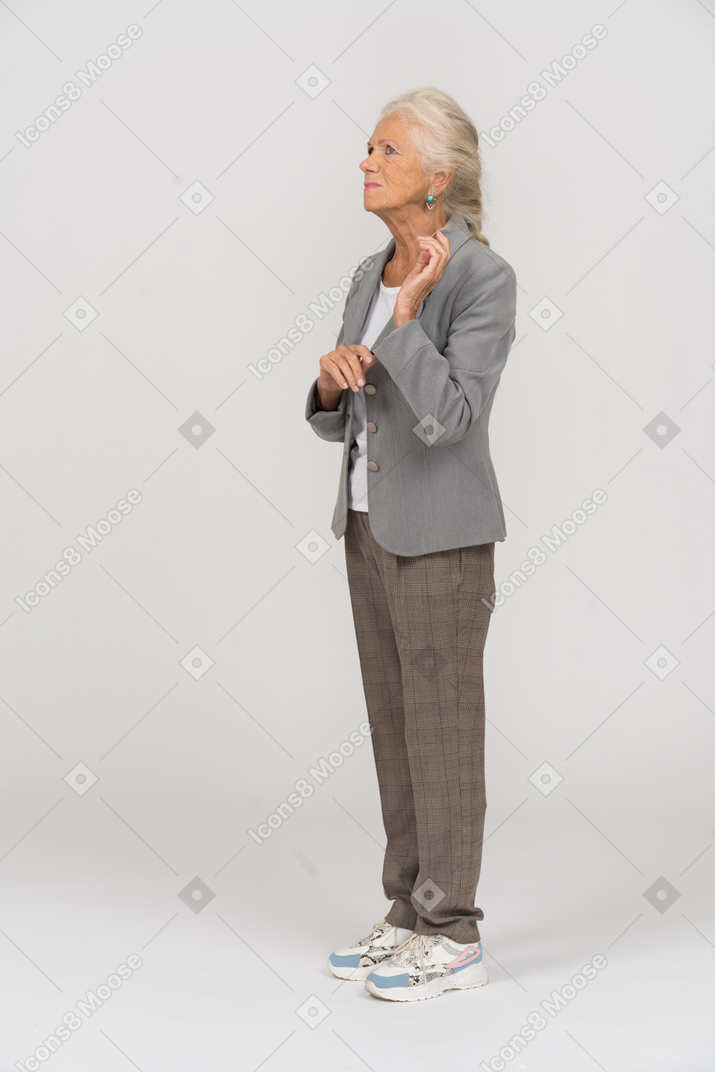 Arrabbiata vecchia donna in abito in piedi di profilo